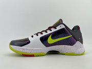 Side profile with white upper, purple panels, green accents, and speckled midsole.