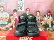 Front view of black Nike high-top sneakers with gold tongue logos and adjustable straps