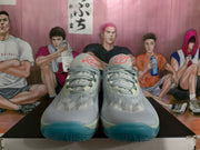 Front view of grey Nike basketball sneakers with red tongue branding and blue-green outsole sections.
