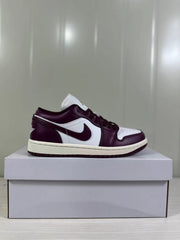 Side profile of one burgundy and white low-top sneaker on a shoebox.
