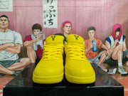 Front view of the yellow sneakers showing perforated toe panels, laces, and black tongue graphics.