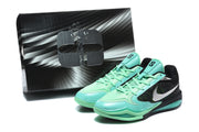 Black and green Nike Kobe basketball shoes pictured beside a matching box