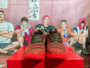 Front view of the dark brown and red sneakers, showing the lace-up design, textured toe box, and red soles.