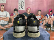 Rear view of black Nike sneakers showing yellow heel details, cream-colored soles, and graphic heel panels.