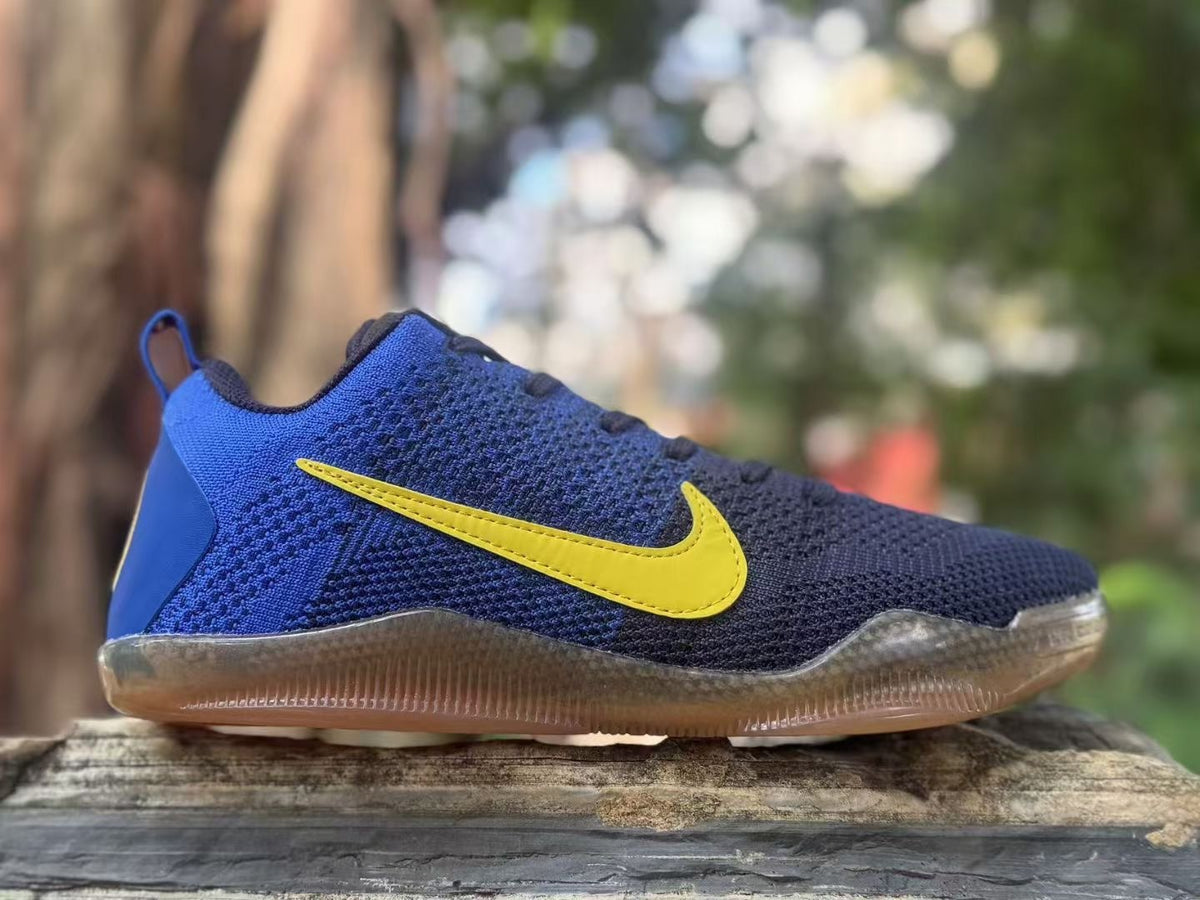 Side view of a blue and navy Nike Kobe 11 sneaker with a yellow Swoosh and translucent brown outsole