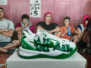Side profile of a white and green Nike basketball sneaker showing the green Swoosh, character-style upper graphics, and sculpted outsole.