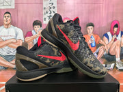 Angled view of paired Nike Kobe camouflage sneakers showing the red Swoosh, black-and-camouflage uppers and heel structure.