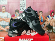 Angled view highlighting the layered black upper, white Swoosh, purple perforated panels, and segmented contrasting outsole.