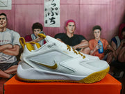 Side view of a white Nike Zoom basketball shoe with a silver panel and gold logo
