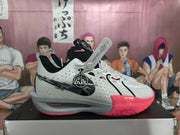 Side view of a white and pink Nike basketball sneaker with visible swoosh branding and a gray midsole.