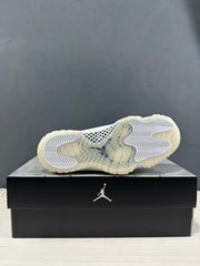 Bottom view of the white sneaker showing patterned traction sections and a translucent outsole.