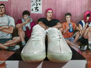 Front view of white Nike basketball shoes with a glossy finish and pale translucent-looking soles