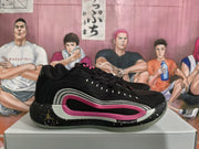 Side view of black Jordan basketball sneakers with pink and light-colored layered side accents on a shoe box.