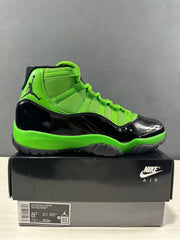 Side view of black and vivid green Air Jordan 11 Retro sneakers displayed on a shoe box; the box label shows EU 42 and style code CT8012 310.