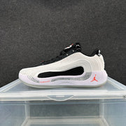Side view of a white, black, and red Jordan low-top basketball shoe.