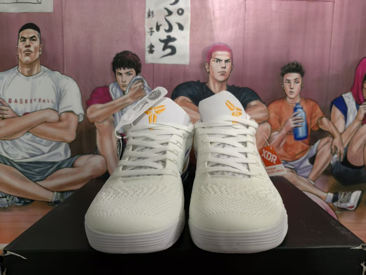 Front view of white Nike basketball sneakers with yellow tongue logos and a purple-and-yellow color scheme visible at the sides.