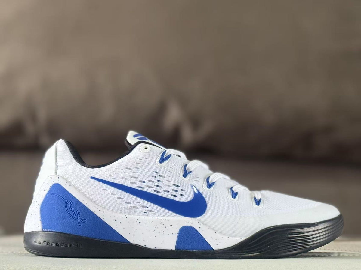 Side view of white and blue Nike Kobe 9 basketball sneakers with a black outsole and speckled midsole.