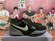 Side profile of a black and grey Nike basketball sneaker with a contrasting swoosh, glossy side panel, and layered outsole.
