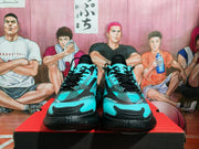 Front view of the aqua and black sneakers showing black laces, aqua toe panels, black overlays, and textured black outsoles.