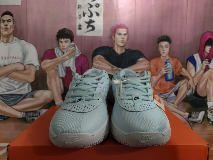 Front view of a pair of blue Nike sneakers with black tongue logos, white midsoles, and perforated toe panels on an orange shoebox.