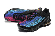 Pair of black Nike Air Max Plus TN sneakers with blue, purple, and pink gradient panels.
