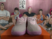 Front view of light grey and pink Nike basketball sneakers with pink laces and textured soles.