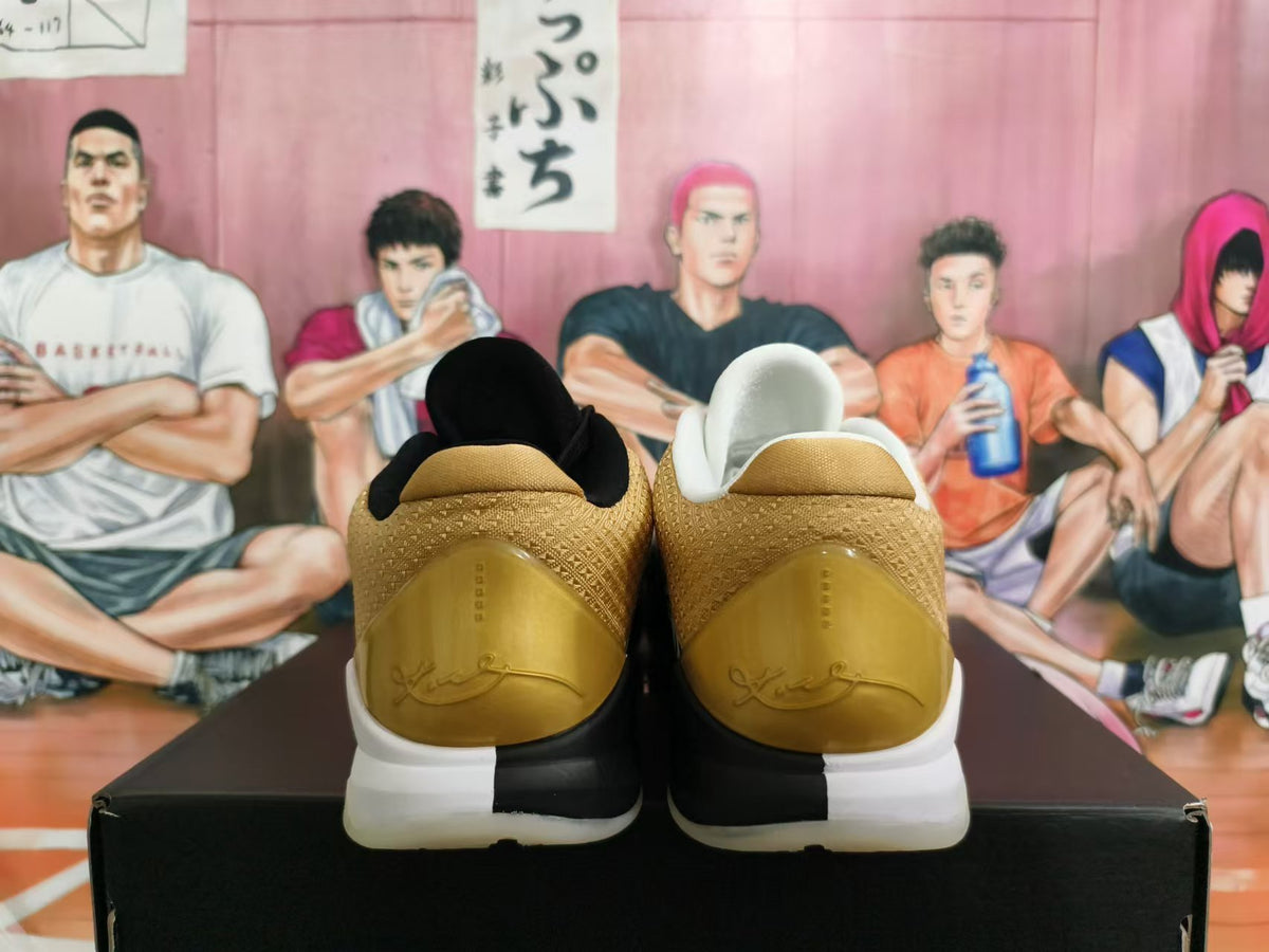 Rear view of white Nike Kobe basketball shoes with gold heel panels and black-and-white sole detailing