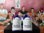 Rear view of white and purple Nike Kobe basketball shoes with signature heel graphics
