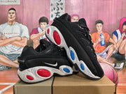 Three-quarter view of two black Nike sneakers displaying the side swooshes, textured uppers and contrasting red and blue sole details.