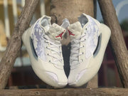 Front view of a pair of white Jordan 39 sneakers with red tongue details