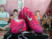 Angled view of the pink and purple Nike sneakers showing the side branding, textured upper, and translucent outsole.