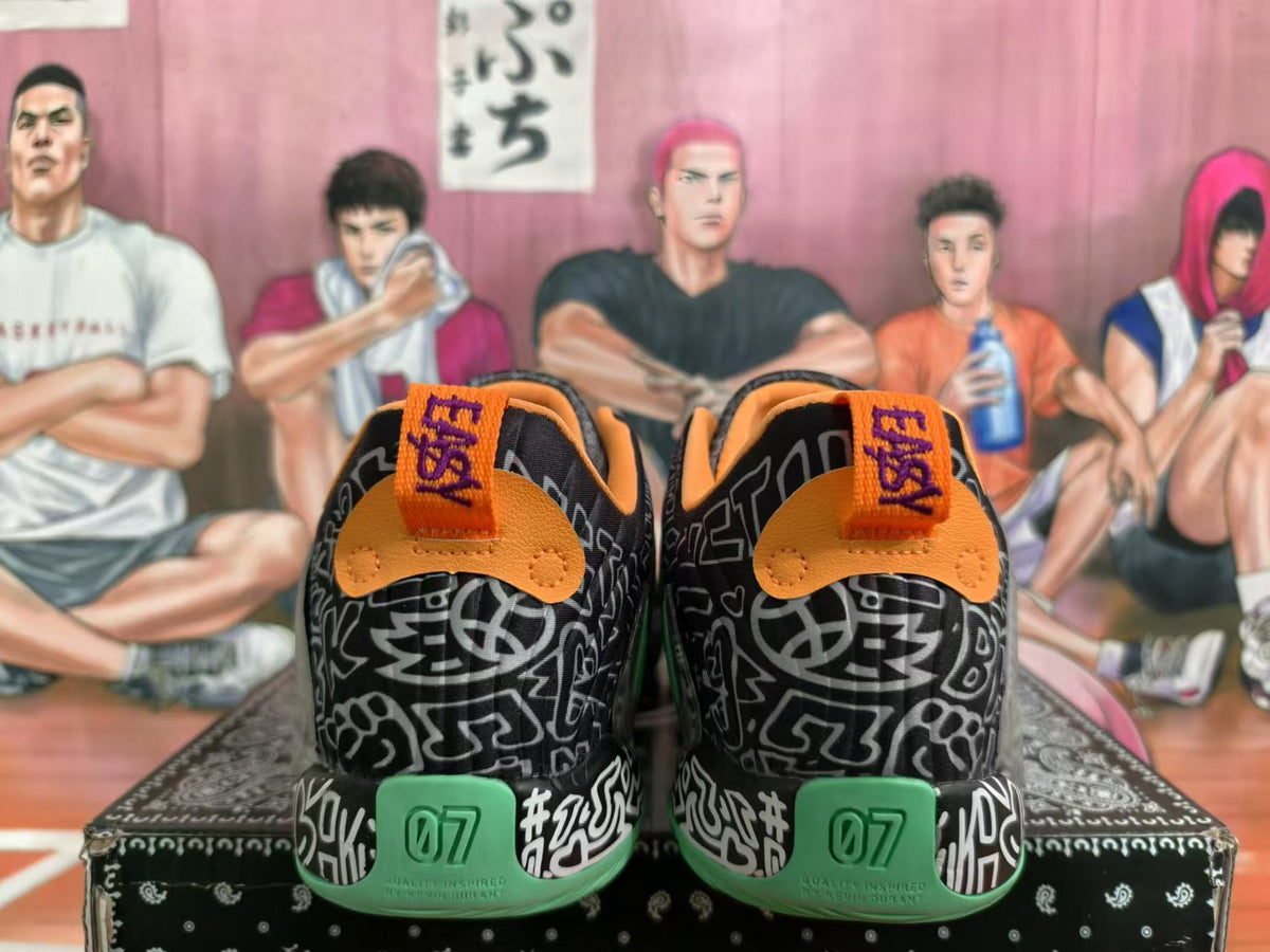 Rear view of black graphic basketball sneakers with orange collars, green heel sections, and KD branding.