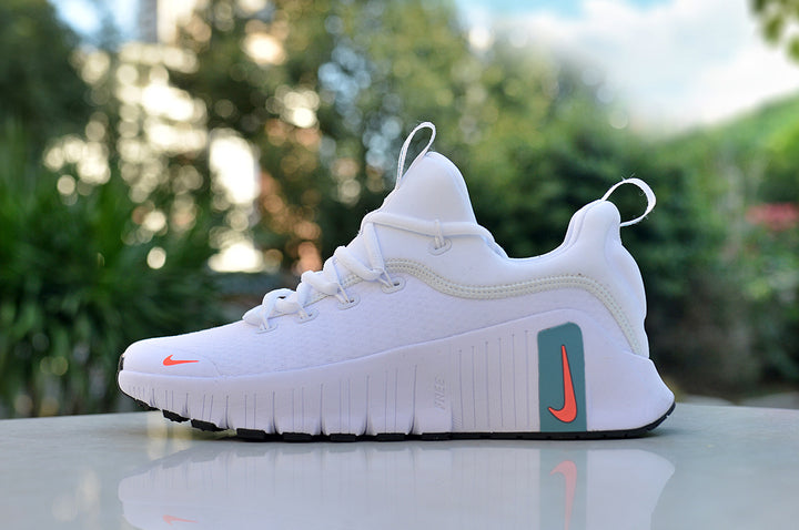 Side view of a white Nike low-top sneaker with teal and coral accents and a grooved sole.