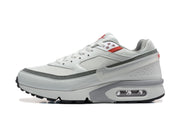Side view of a white Nike sneaker with grey trim, red accents, a translucent Swoosh, and a visible heel air unit.
