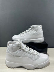 White Air Jordan 11-style high-top sneakers shown from the side with a black shoebox.
