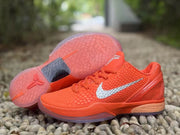 Orange sneaker shown beside its outsole, including the visible tread pattern and Kobe branding.