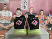 Rear view of the pair showing black heel panels with pink embroidered graphics and lime-green outsole sections.