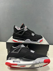 Pair of black Jordan Air Jordan 4 sneakers shown from the side and outsole angles on a shoebox.
