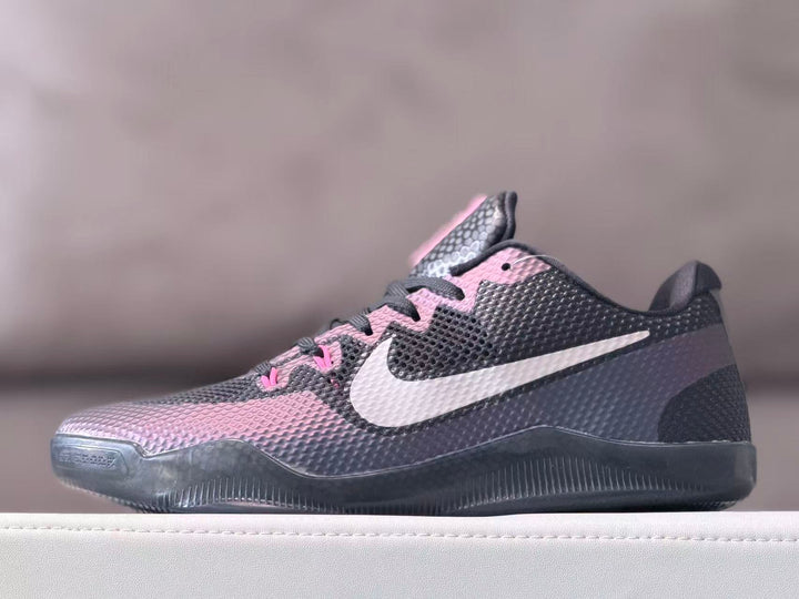 Side view of a charcoal gray Nike Kobe 11 low-top shoe with pink accents and a white Swoosh.