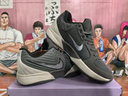 Angled view of the pair of gray and black Nike basketball sneakers showing the side branding, padded upper, layered midsoles, and outsole tread.