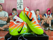 Angled side view of the orange and neon green Nike sneakers displayed on a shoebox.