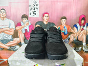 Front view of black Nike sneakers with black laces and glossy black soles.