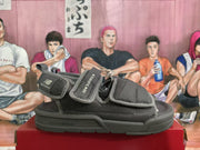 Black and gray New Balance sandals shown from the side on a red box.