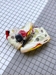 Pair of off-white sneakers photographed together with red and black accessories.