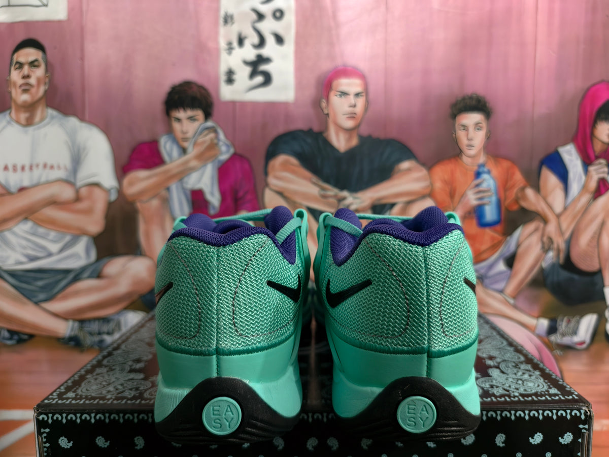 Rear view of gray-green Nike sneakers showing black Swoosh details, purple collar lining, and black heel sections.
