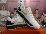 Angled view of white Nike KD basketball sneakers showing gold Swooshes, black heel panels and contrasting soles.