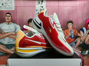 Angled view of the red and white Nike basketball sneakers showing the side branding, heel details, and translucent outsole.