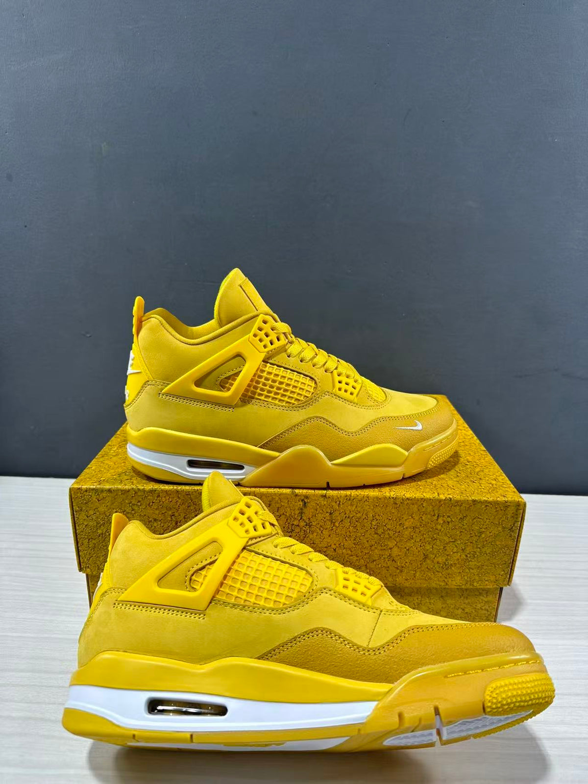 Pair of yellow Jordan Air Jordan 4 sneakers shown from the side on a matching textured shoebox.