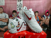 Angled view of the white Nike basketball sneakers displaying the red Swoosh, textured upper, animal graphics, and thick patterned outsole.
