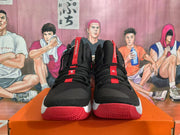 Front view of black high-top basketball shoes with red accents and red outsoles.